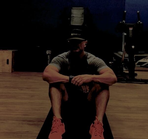 A man sitting on the ground in front of a gym.